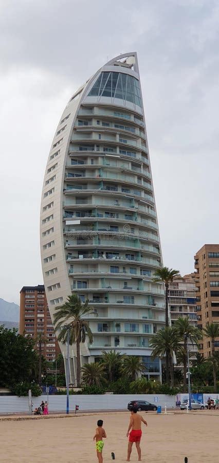 A Modern Curved Building With Multiple Balconies Located Near A Sandy A Modern Curved Building With Multiple Balconies Located Near A Sandy